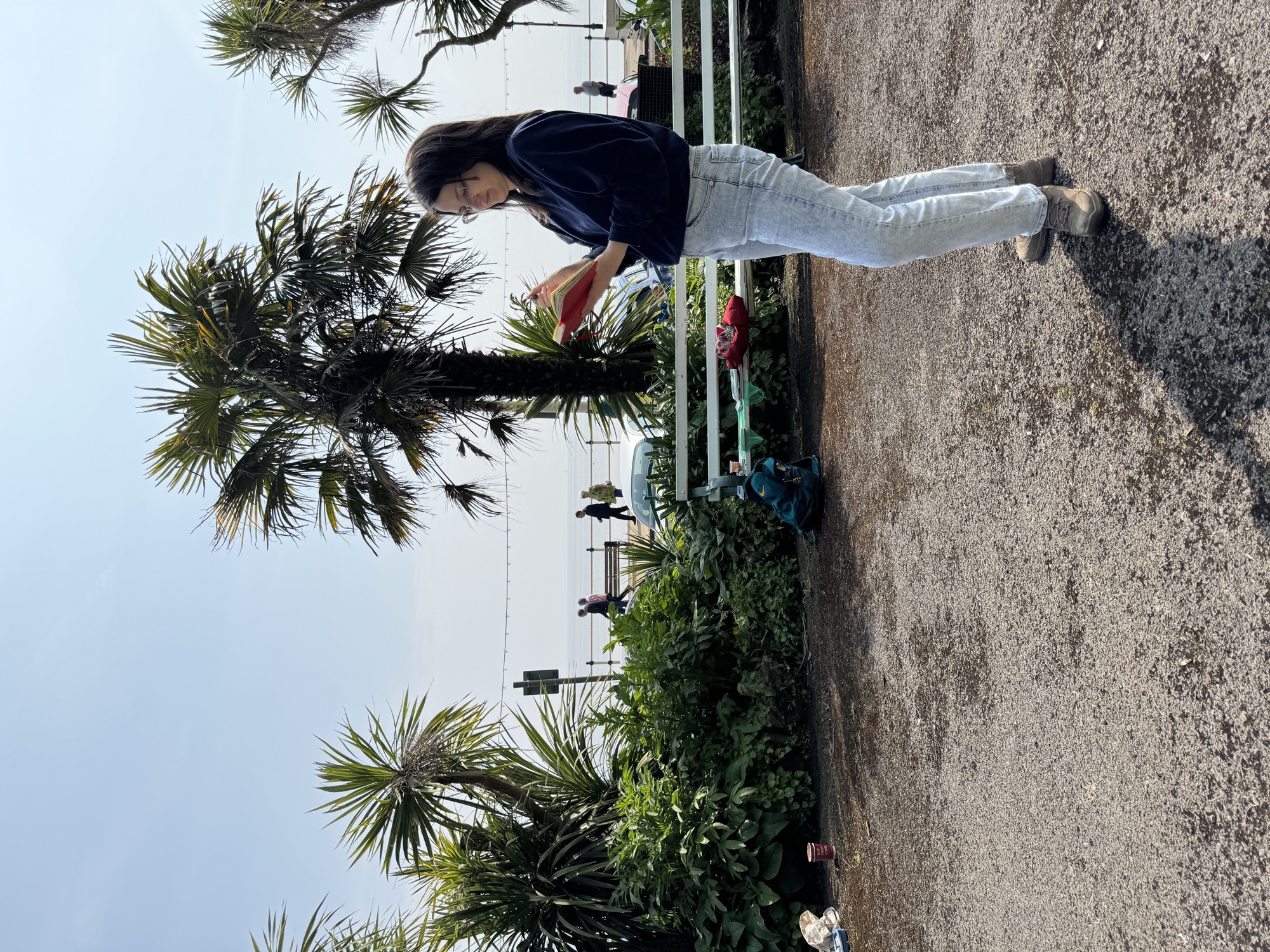 Ksenia Kudelkina sketching in Italian Gardens Penarth with palm trees and the sea behind