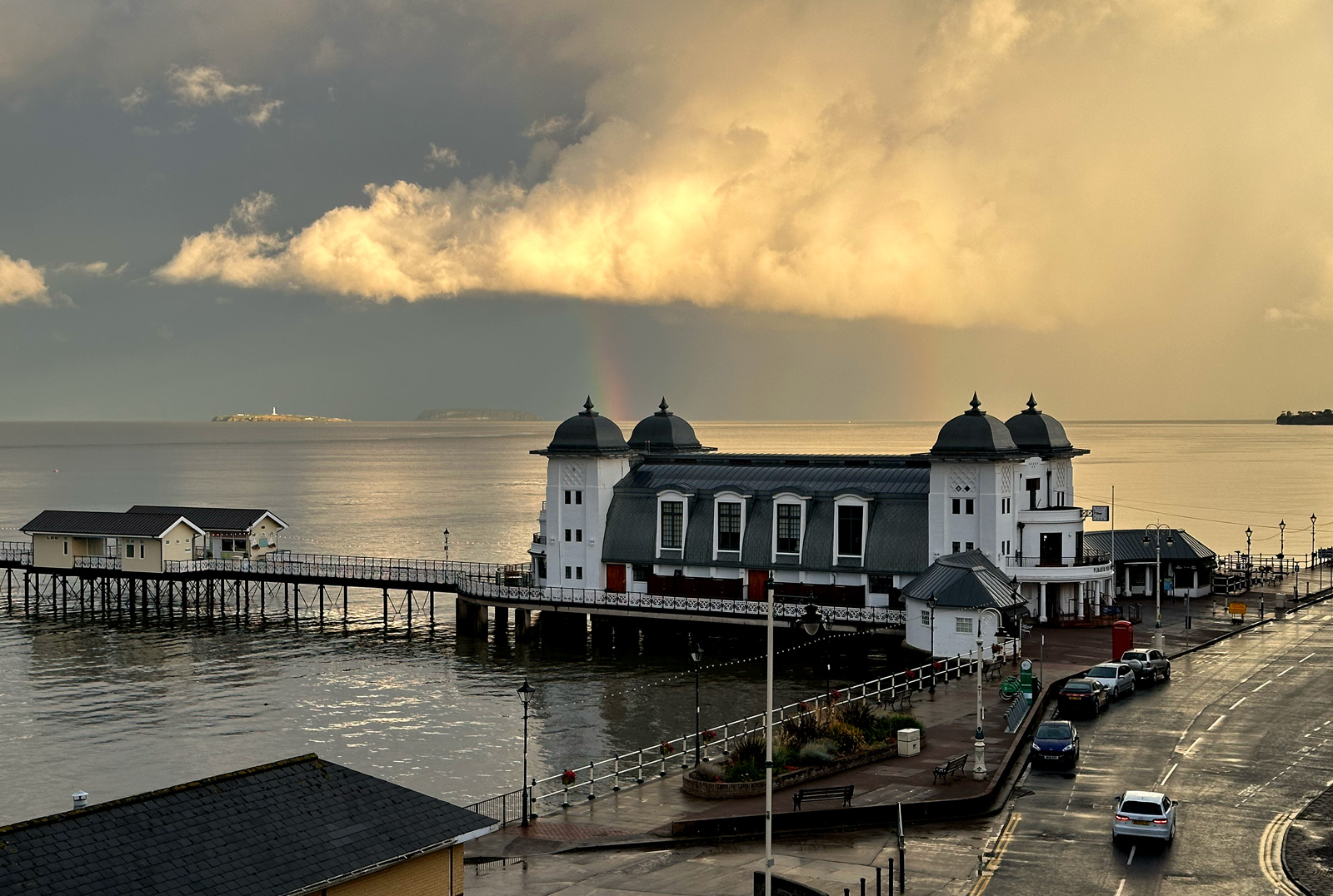 Penarth Pier under storm clouds with a rainbow over the Bristol Channel